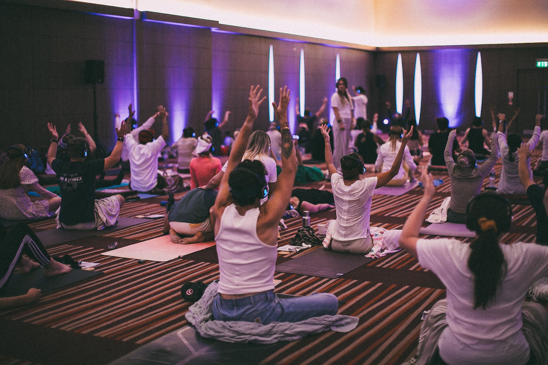 Hundreds of people with arms raised during a breathwork session